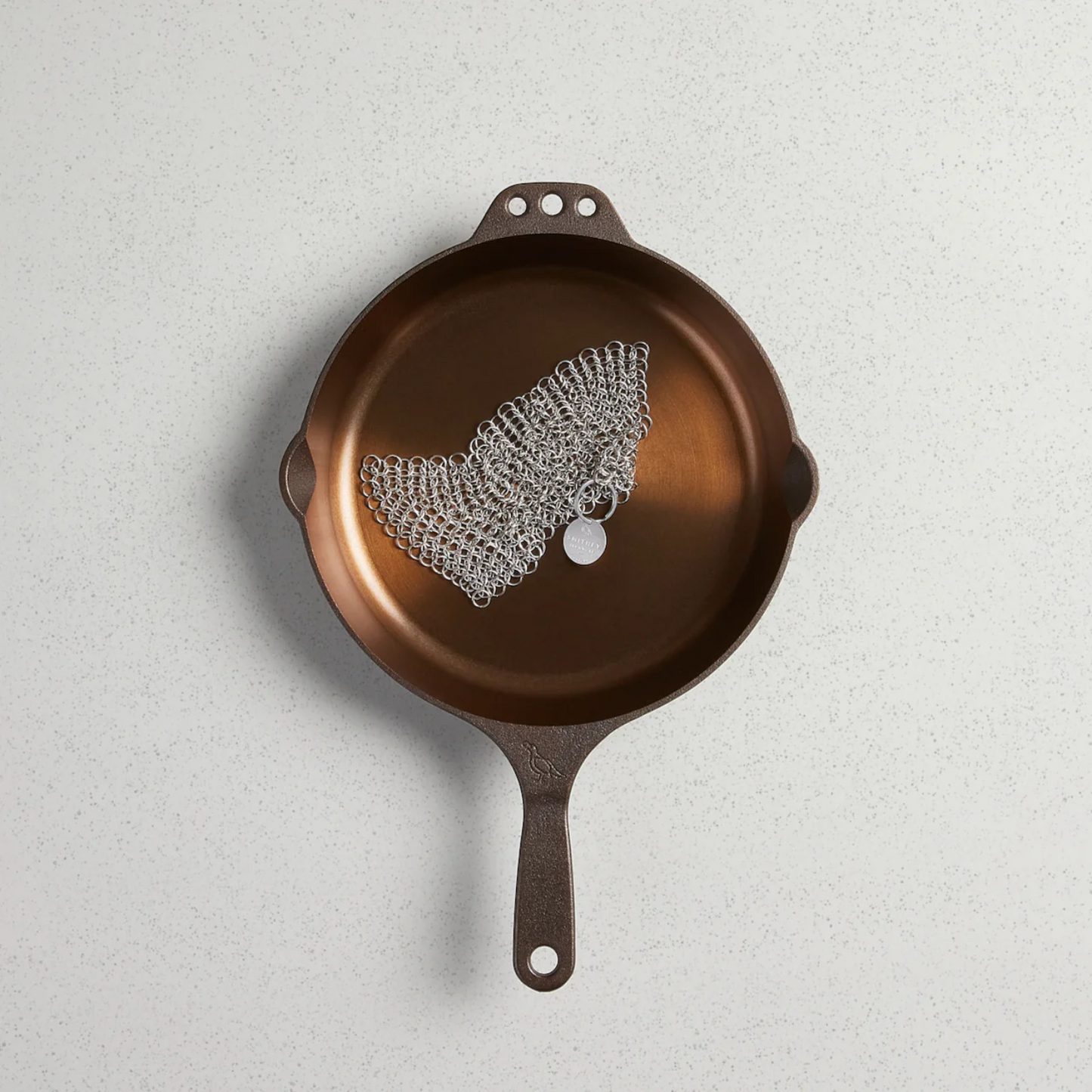Brown cast iron skillet with decorative lace on a light gray background