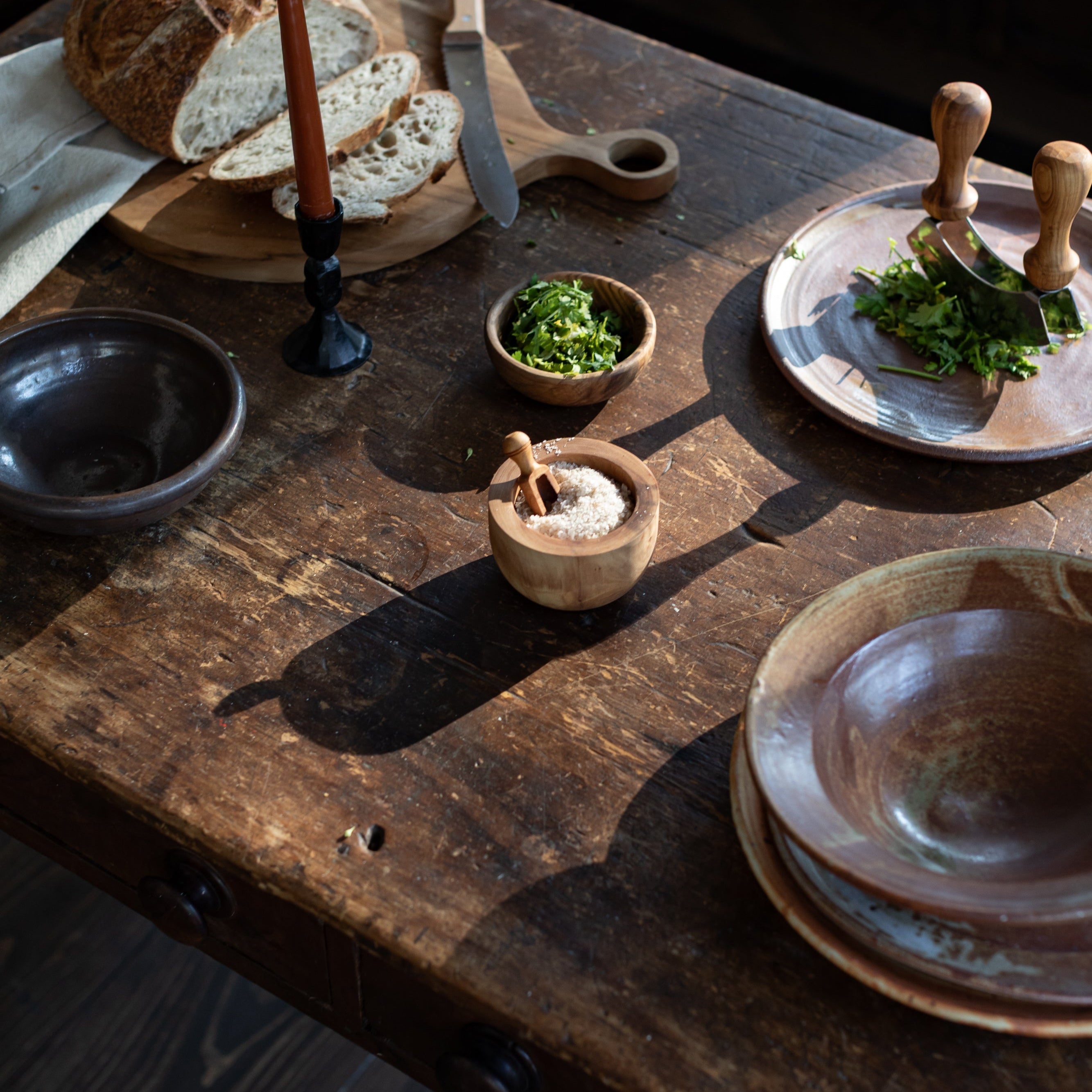 Wooden table with rustic kitchen items including bread, bowls, and a knife.