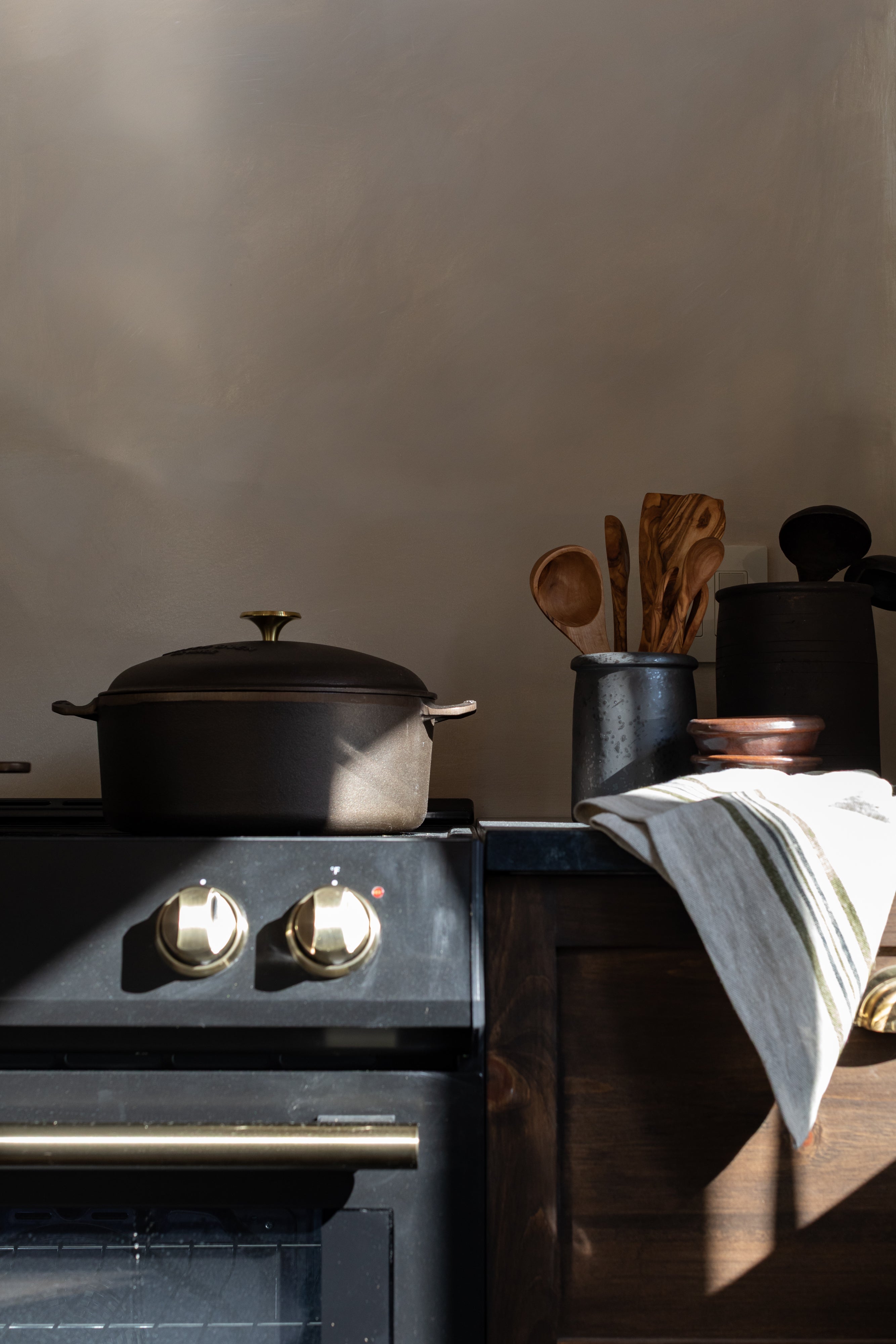 Stove with cast iron pot and olivewood spoons on a soapstone countertop