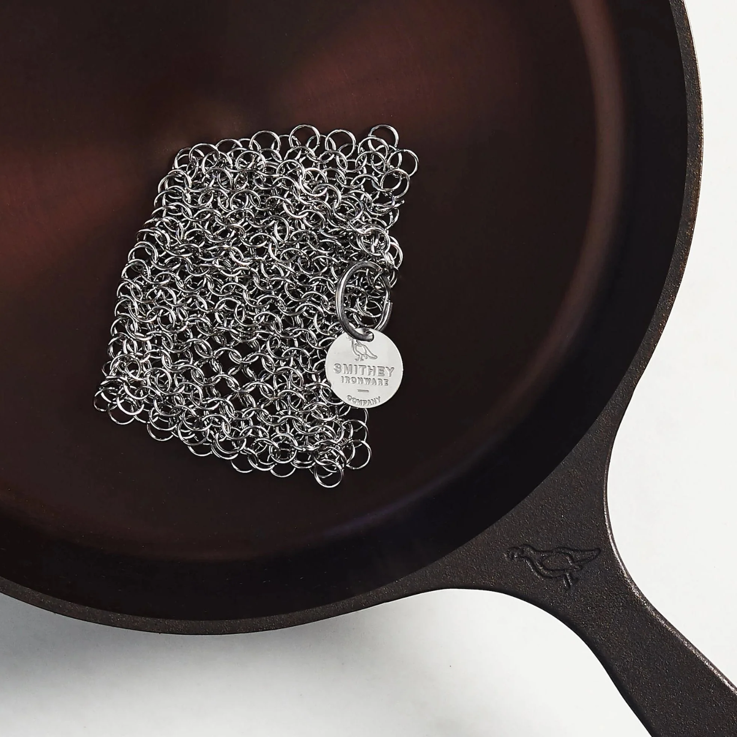 Cast iron skillet with chainmail scrubber on a white background