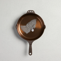 Brown cast iron skillet with decorative lace on a light gray background