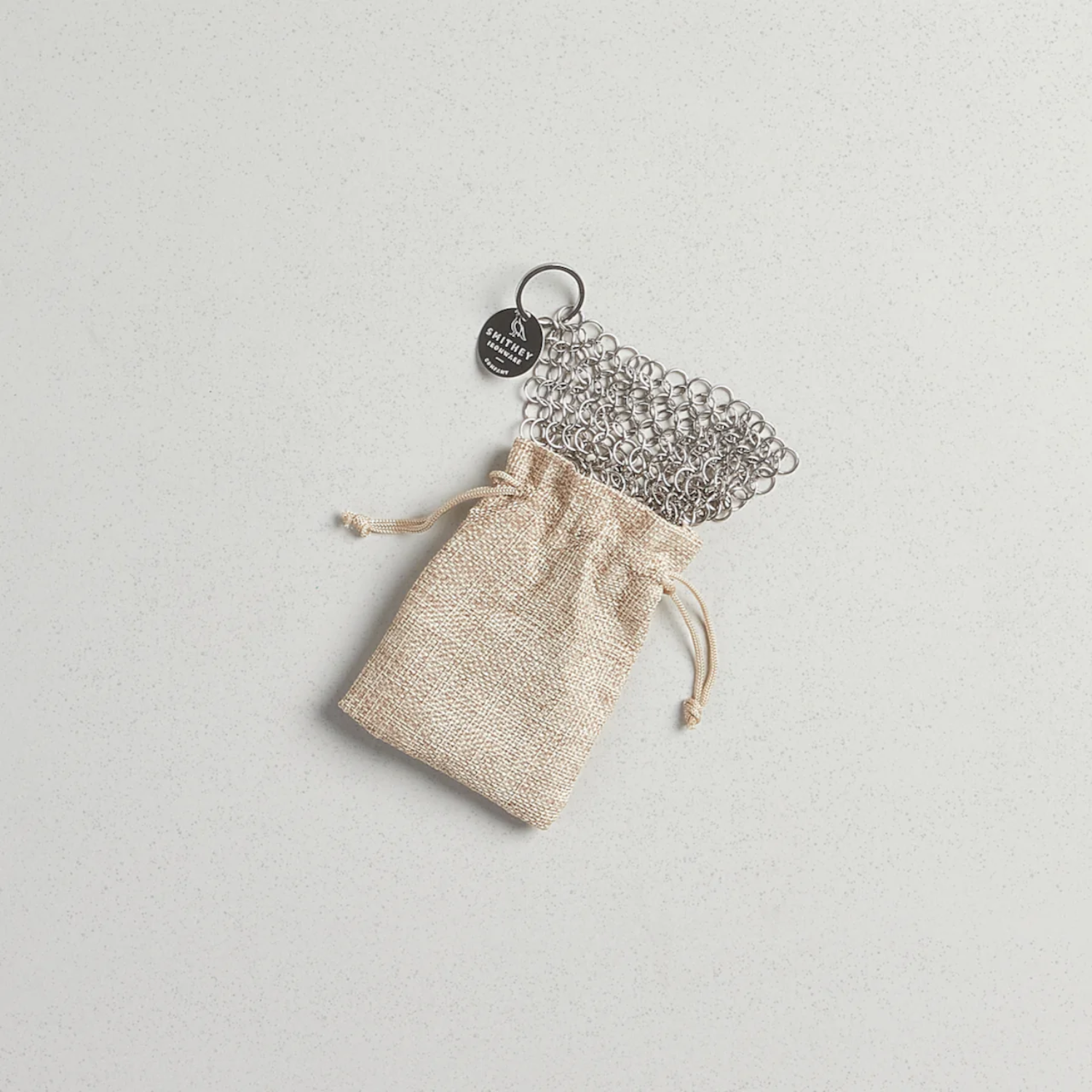 Metal chainmail scrubber with a drawstring pouch on a light gray background