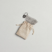 Metal chainmail scrubber with a drawstring pouch on a light gray background