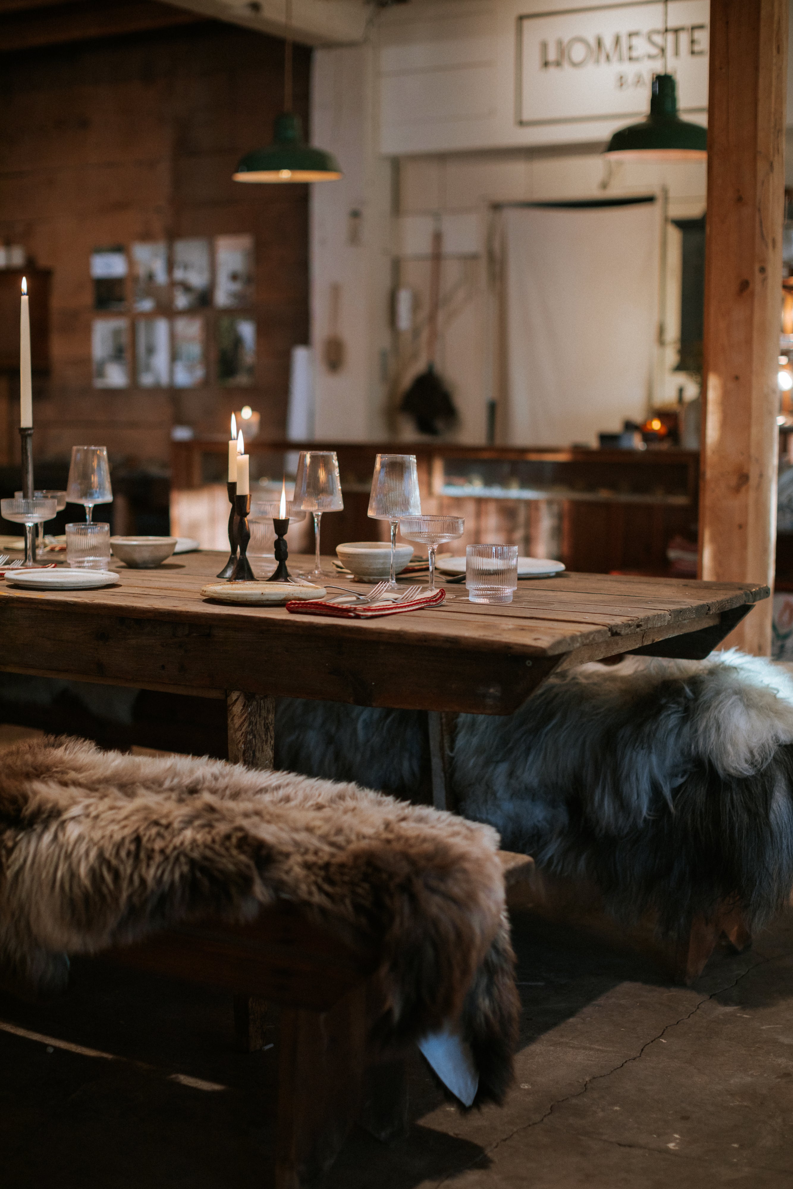 Dining area with wooden table and chairs covered in fur, rustic decor.